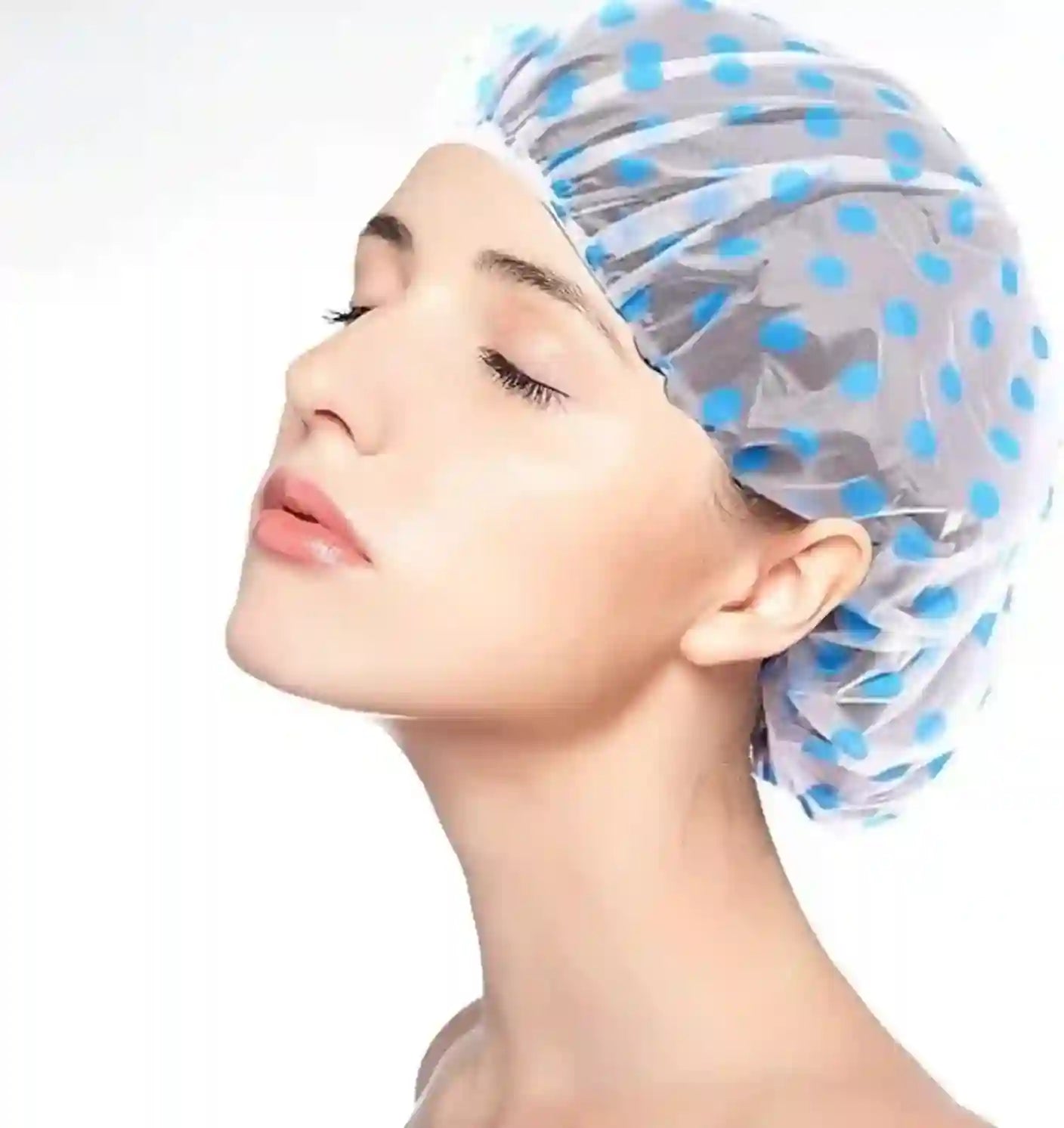 Woman wearing a blue and white polka dot shower cap on a white background