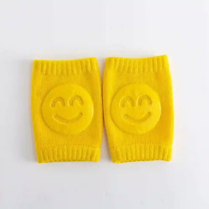Pair of yellow knee pads with smiley face designs on a white background