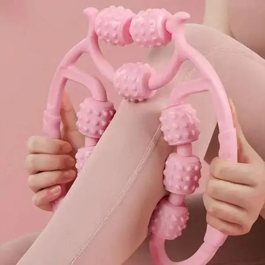 Pink handheld massager being used on a leg against a pink background