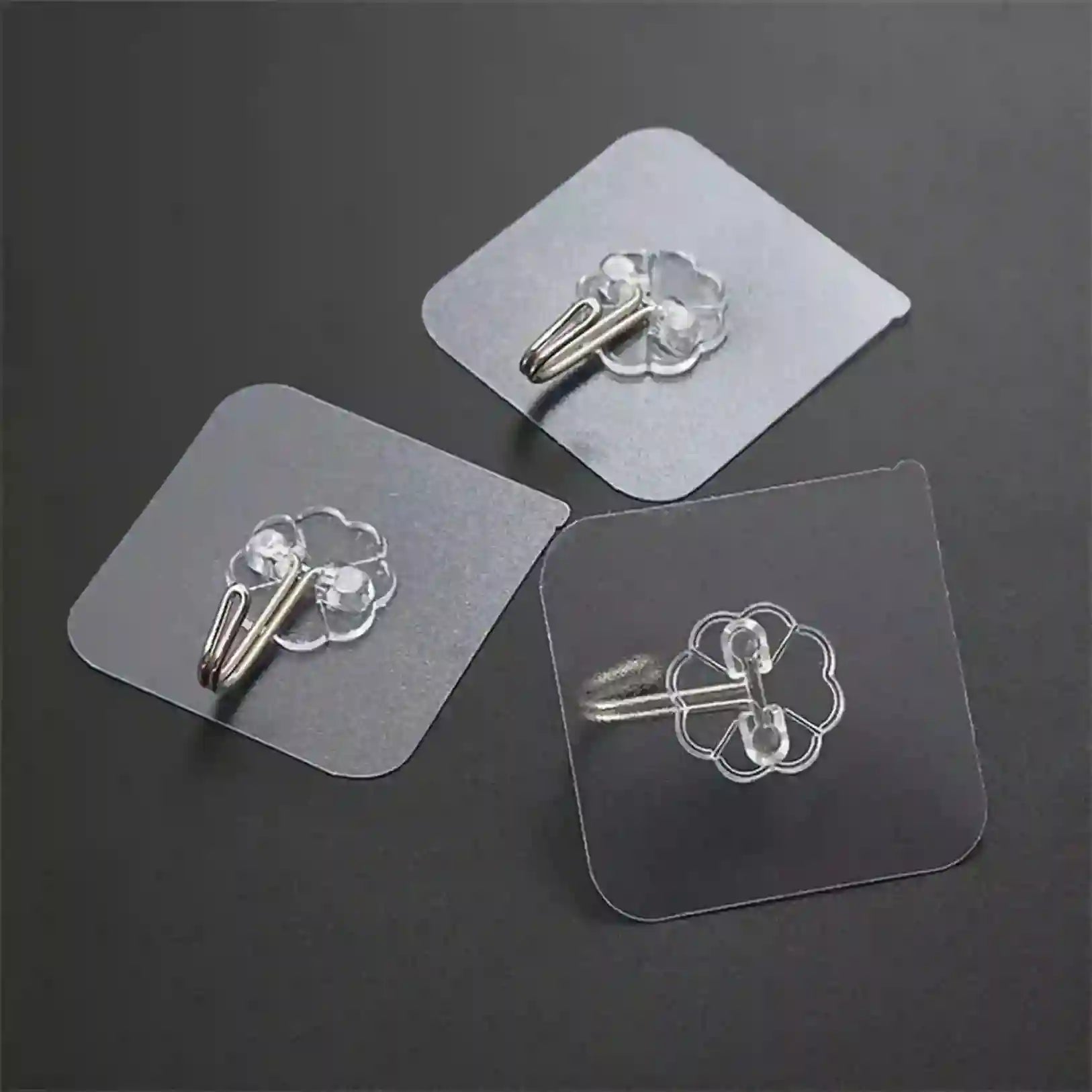Three clear adhesive hooks on a dark gray background