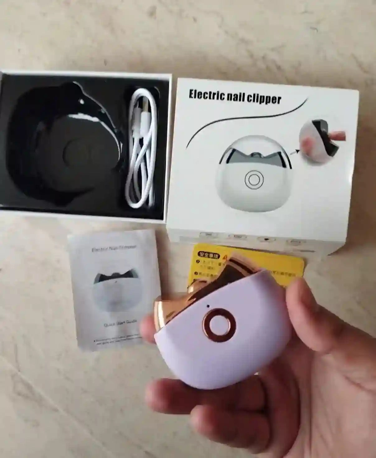 Electric nail clipper with packaging and accessories on a wooden surface