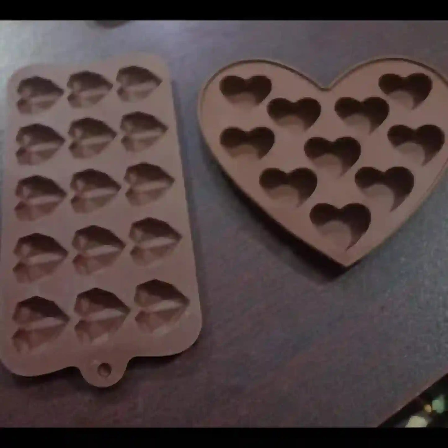 Two silicone molds, one with heart shapes and the other with diamond shapes, on a flat surface.