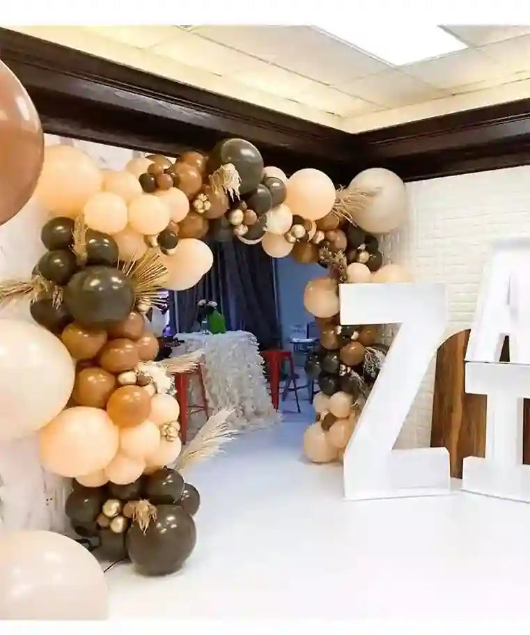 Balloon arch with gold, brown, and beige balloons in a room setting.