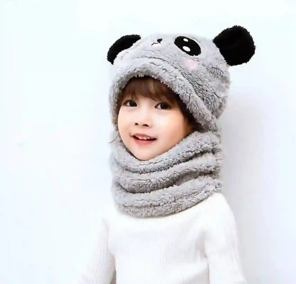 Child wearing a gray panda hat and scarf on a white background
