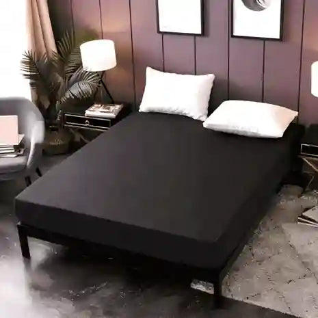 Black bed cover on a bed in a bedroom setting with decor elements.
