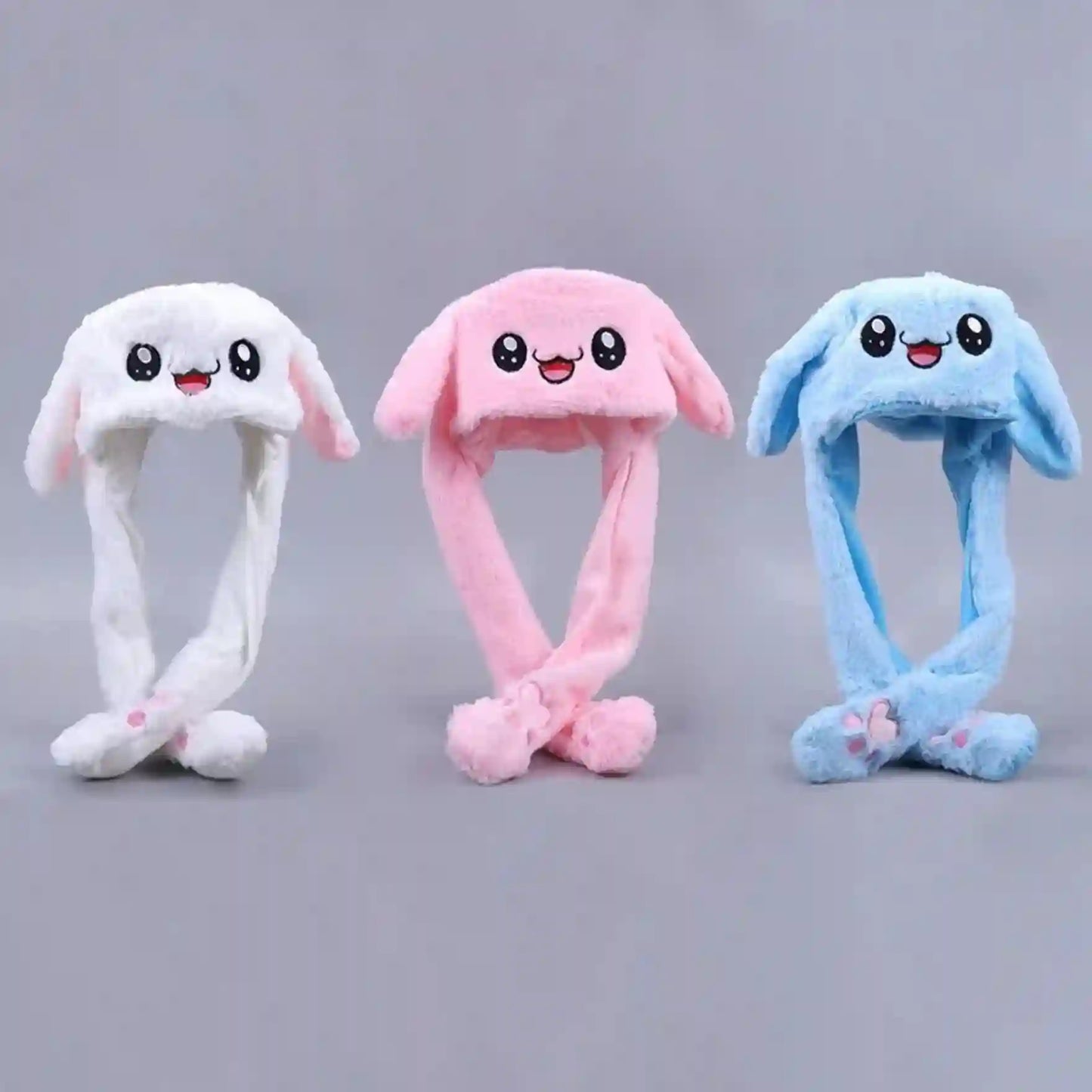 Three colorful plush bunny hats on a gray background