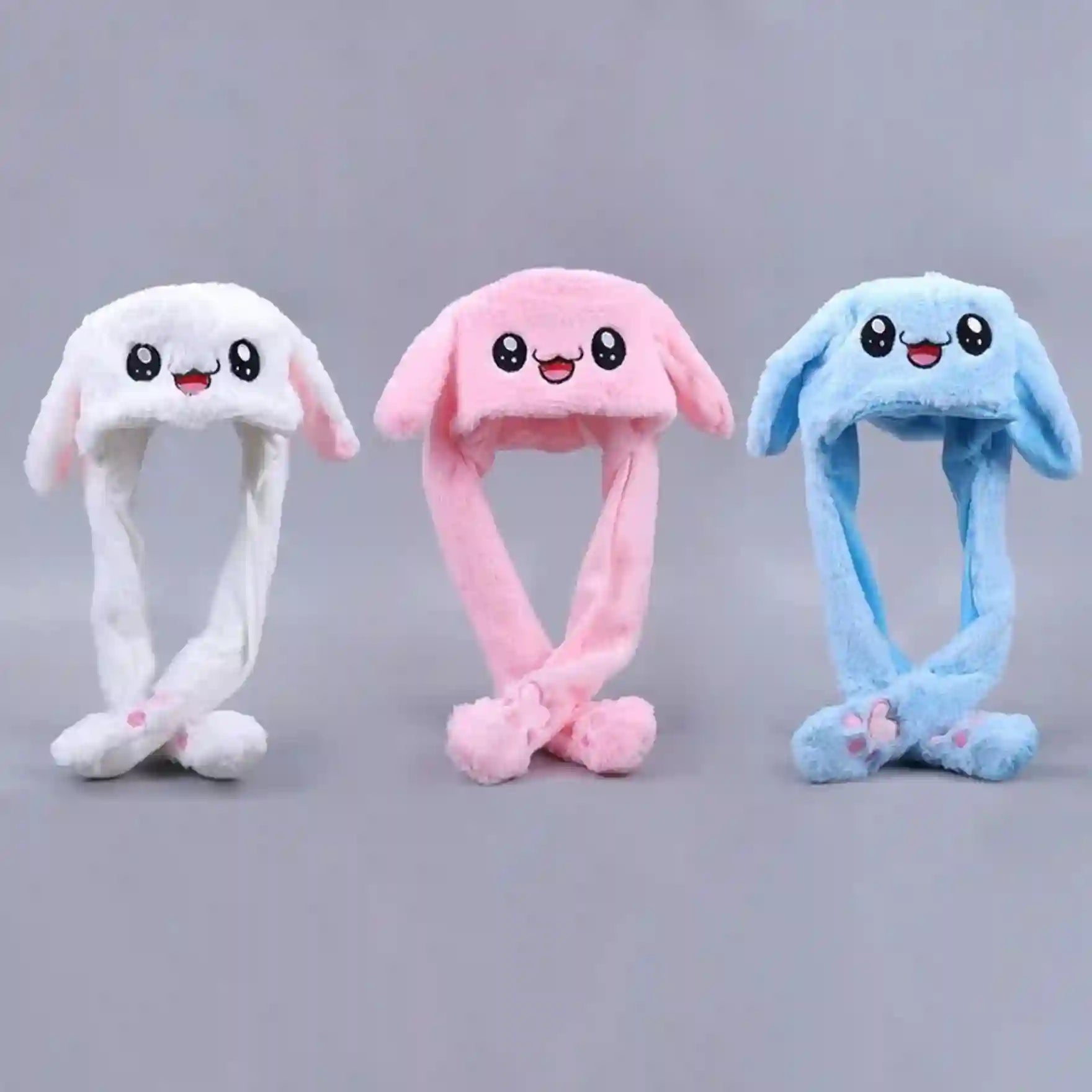 Three colorful plush bunny hats on a gray background