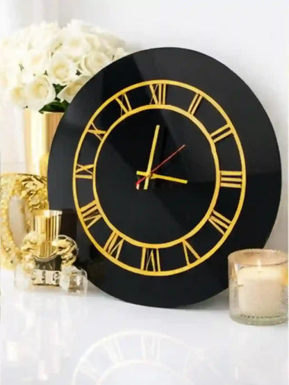 Black wall clock with gold Roman numerals on a decorative surface with candles and flowers.