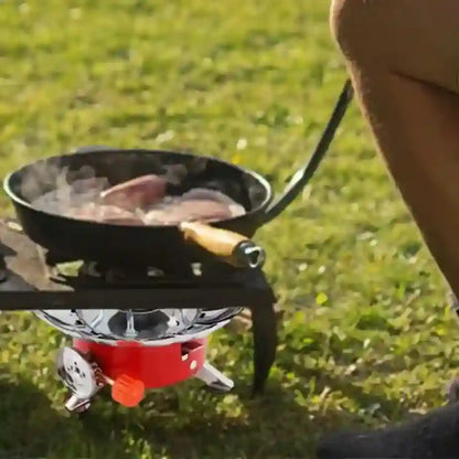 Person cooking on a portable stove with a frying pan outdoors