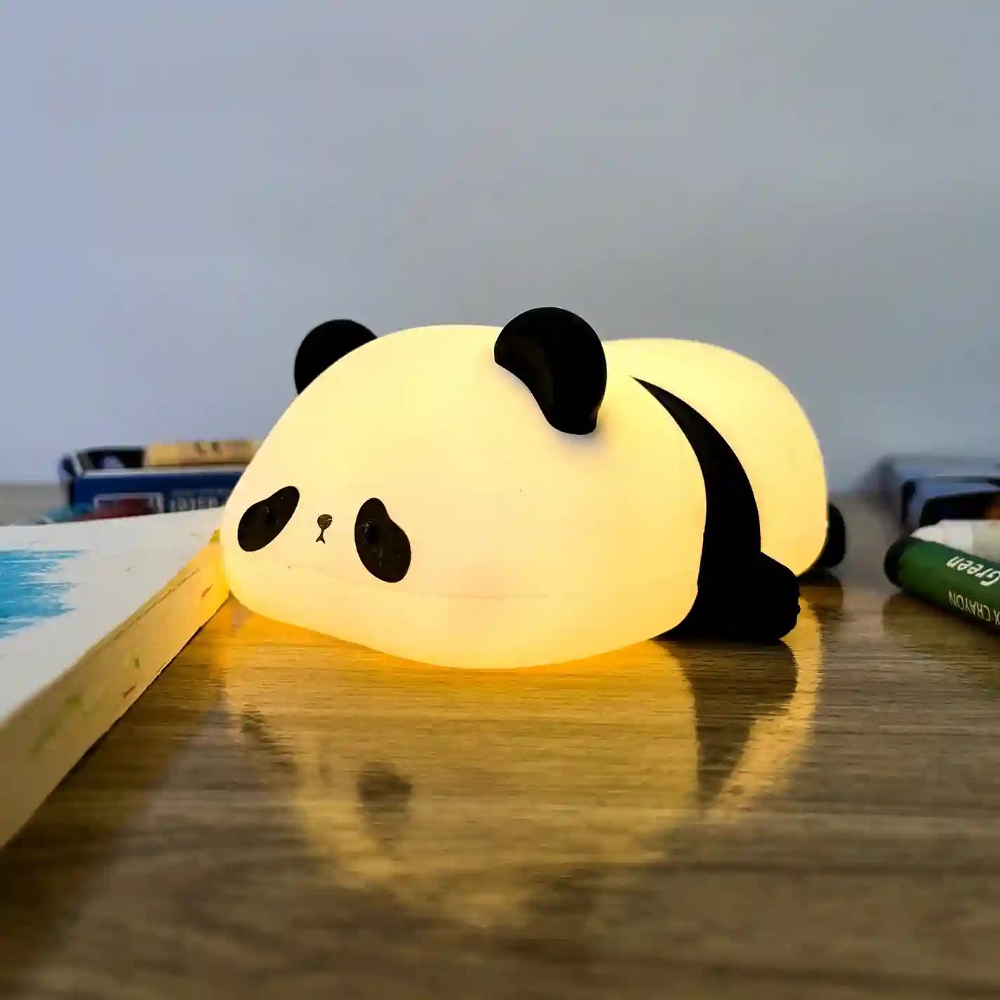 Panda-shaped night light on a wooden surface with books in the background