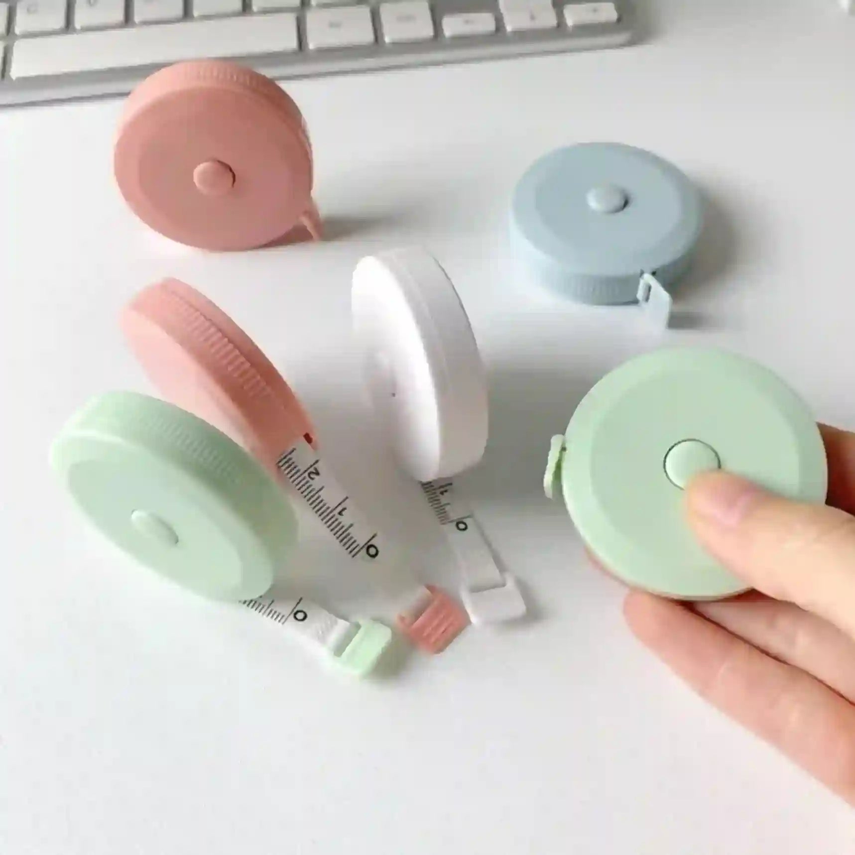Collapsible measuring tape in pastel colors on a white surface with a keyboard.