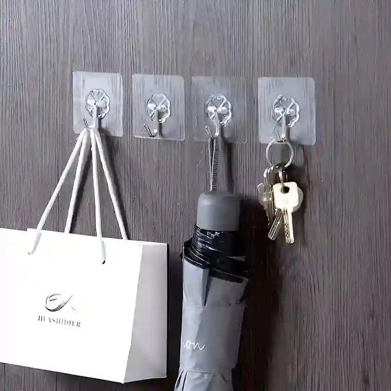 Clear wall hooks holding a bag, umbrella, and keys on a wooden surface.
