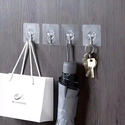 Clear wall hooks holding a bag, umbrella, and keys on a wooden surface.