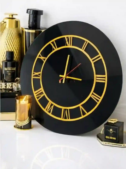 Black clock with gold Roman numerals on a white surface with decorative items.