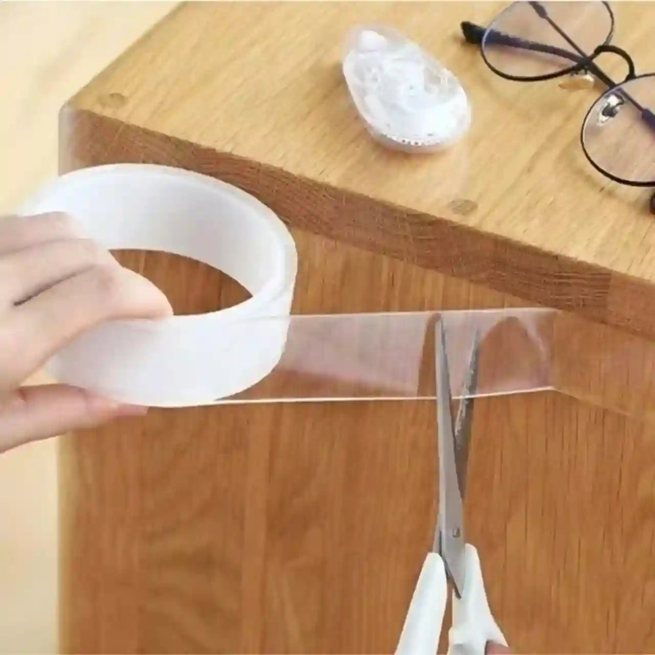 Clear tape being cut with scissors on a wooden surface