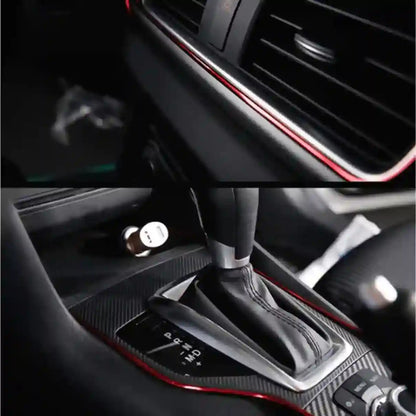 Car interior with air vent and gear shift area, featuring red accents.