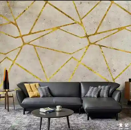 Modern living room with a black sofa against a geometric gold wall design.