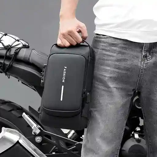 Person holding a black motorcycle bag with 'FASHION' branding on a motorcycle.