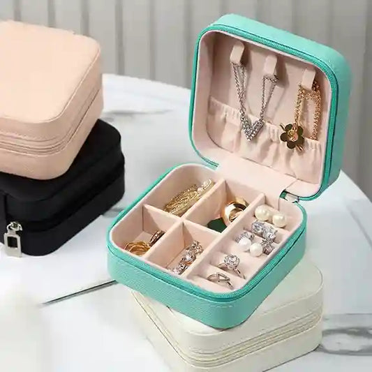 Jewelry box with compartments filled with necklaces, earrings, and rings on a light surface.