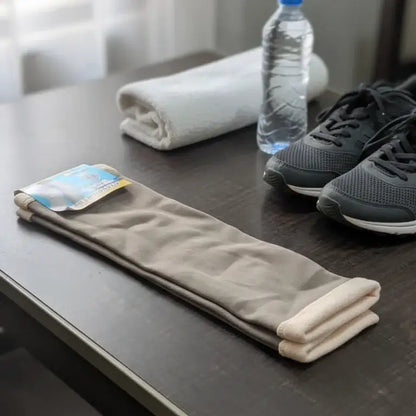 Folded beige pants, gray sneakers, water bottle, and smartphone on a dark surface.