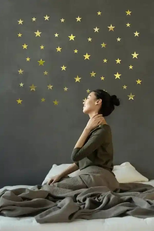 Woman sitting on a bed with a star-patterned wall behind her