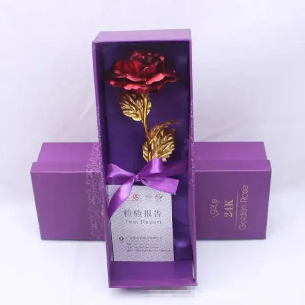 Gold rose in a purple box with a bow on a white background