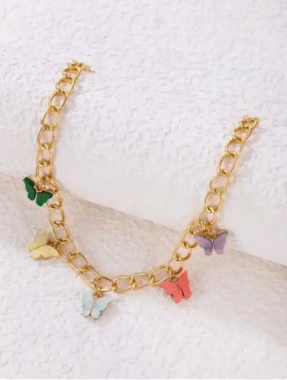 Gold chain bracelet with colorful butterfly charms on a textured white background