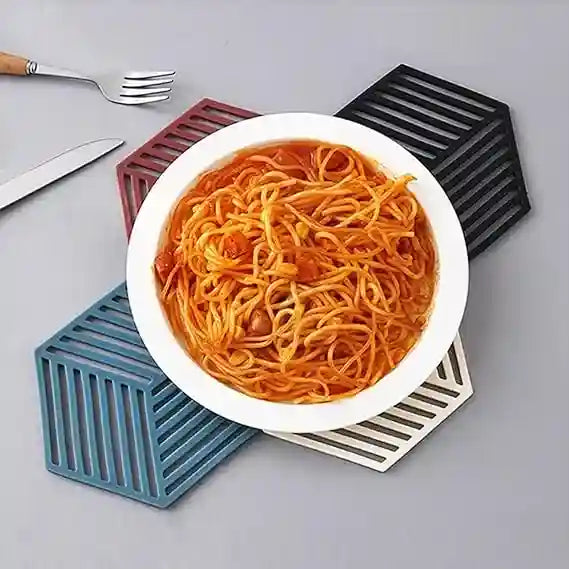 White bowl of spaghetti on a gray surface with geometric coasters.