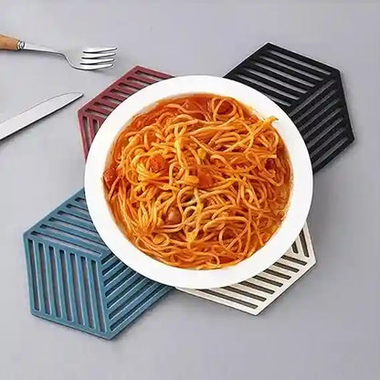 White bowl of spaghetti on a gray surface with geometric coasters.