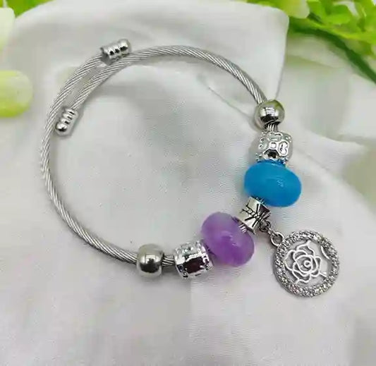 Silver bracelet with colorful beads and a rose charm on a white background