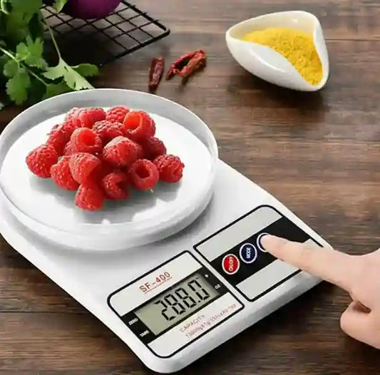 Digital kitchen scale with raspberries on a wooden surface