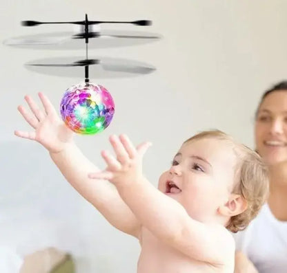 Child playing with a colorful flying ball toy, with a woman in the background.