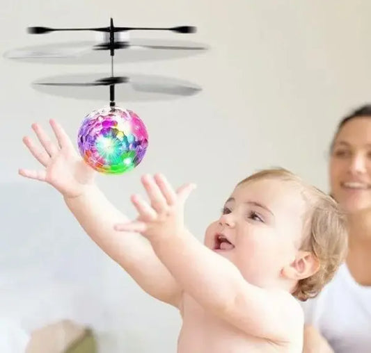 Child playing with a colorful flying ball toy, with a woman in the background.