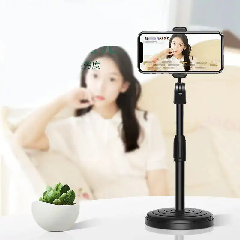 Phone holder on a stand with a blurred background of a person sitting on a couch.