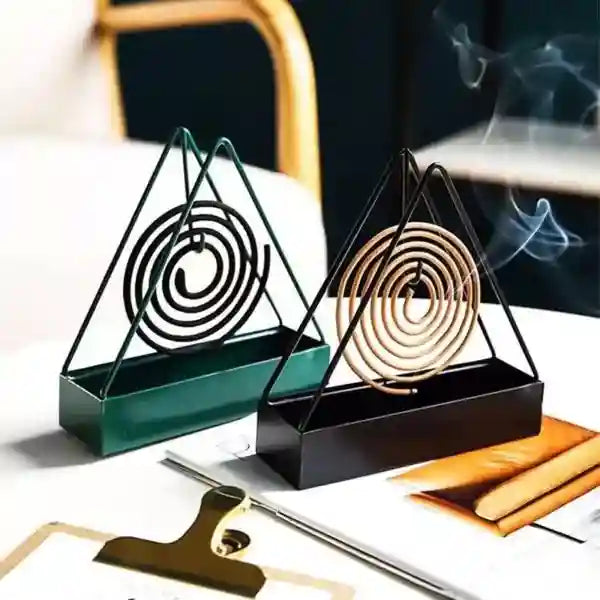 Two incense holders with spiral incense on a table with a blurred background
