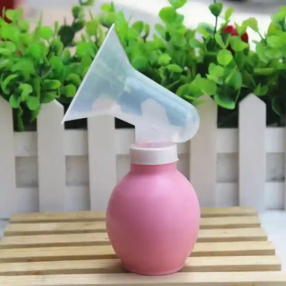 Pink spray bottle with a transparent nozzle on a wooden surface with green plants in the background