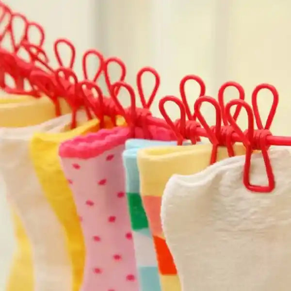 Colorful socks hanging on a red wire rack against a light background