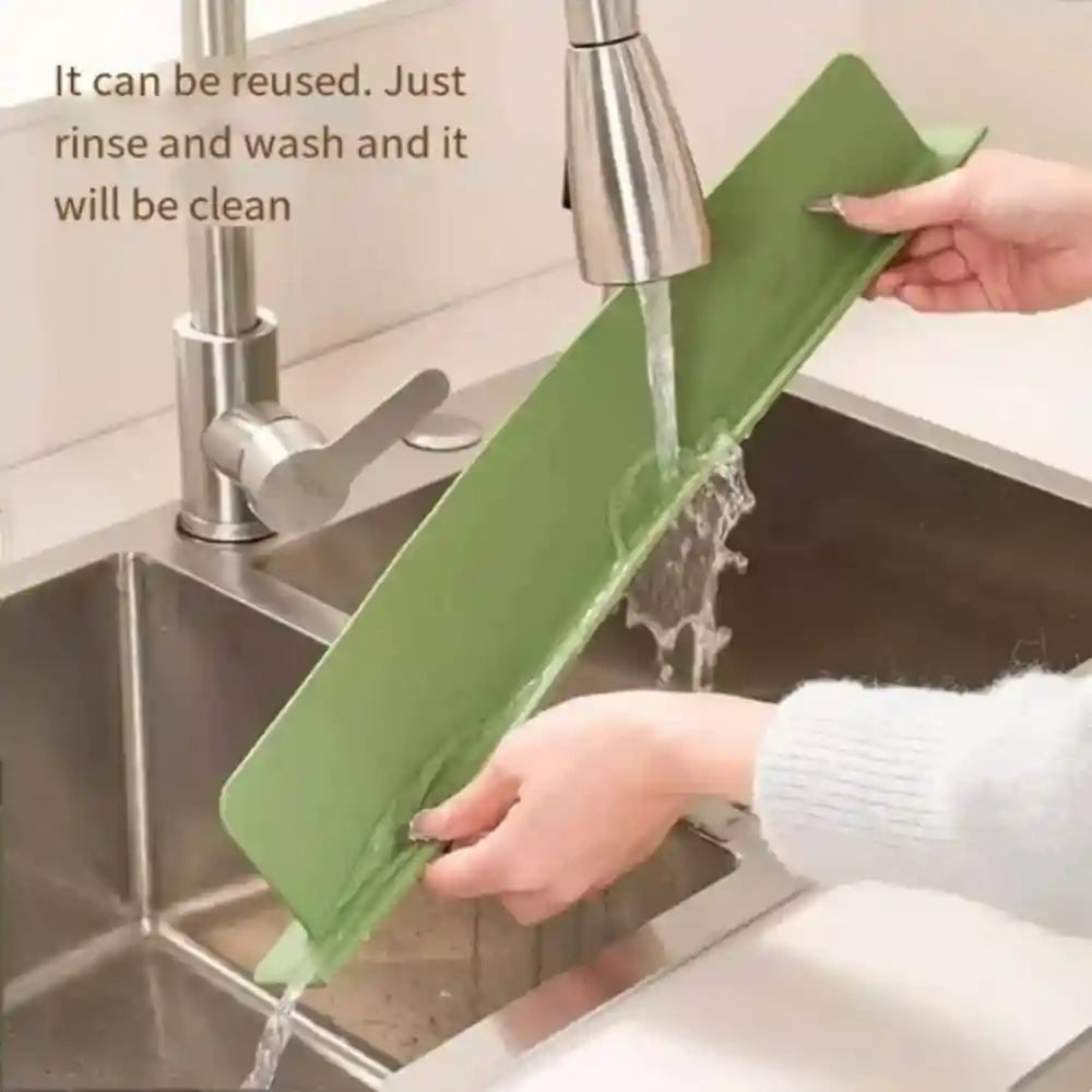 Person washing a green cutting board under running water in a kitchen sink.