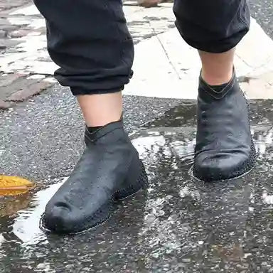 Black rubber boots worn on wet pavement
