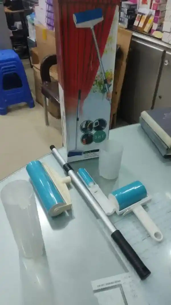 Cleaning tools including a broom and dustpan on a glass table with a store setting in the background.