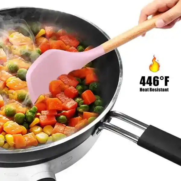 Pink spatula stirring vegetables in a frying pan with a heat-resistant indicator.