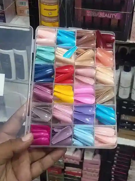Box of colorful nail tips held by a hand with a blurred background