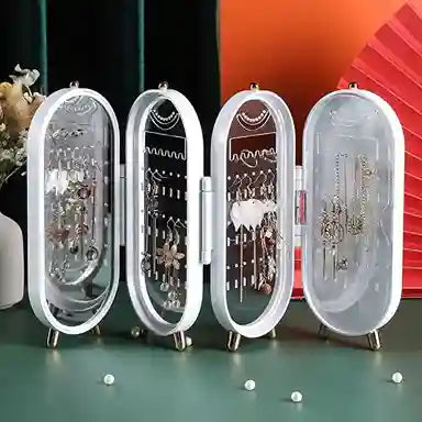 Set of four clear jewelry display cases on a green surface with a colorful background.