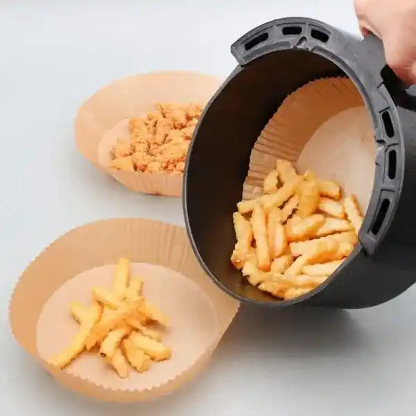 Black air fryer basket with crispy fries on a light gray background