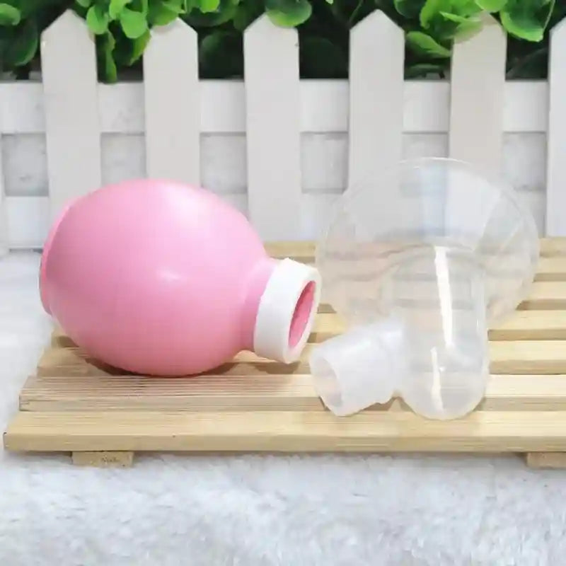 Pink and clear plastic items on a wooden surface with a white picket fence background
