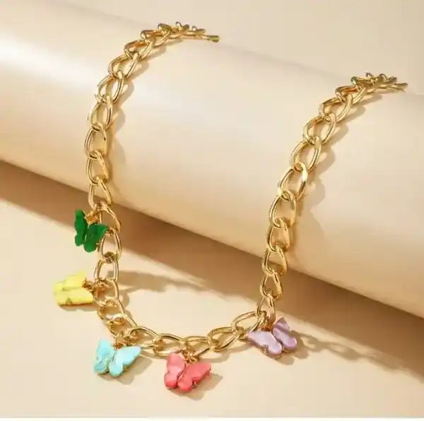Gold chain bracelet with colorful butterfly charms on a beige background
