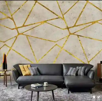 Modern living room with a black sofa against a geometric gold wall design.