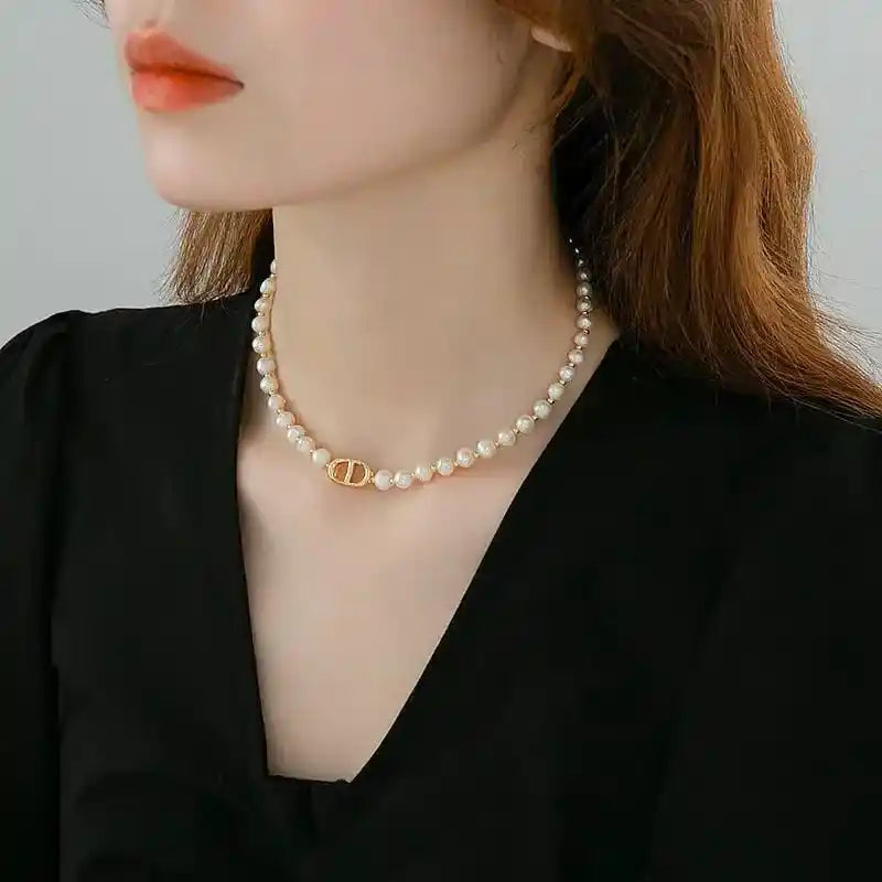 Pearl necklace with a gold clasp worn by a person against a neutral background