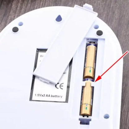Close-up of a device with a battery compartment and a battery labeled '1.5Vx2 AA battery' on a wooden surface.