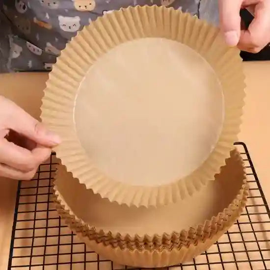 Person preparing a round baking pan with a brown paper lining on a cooling rack.